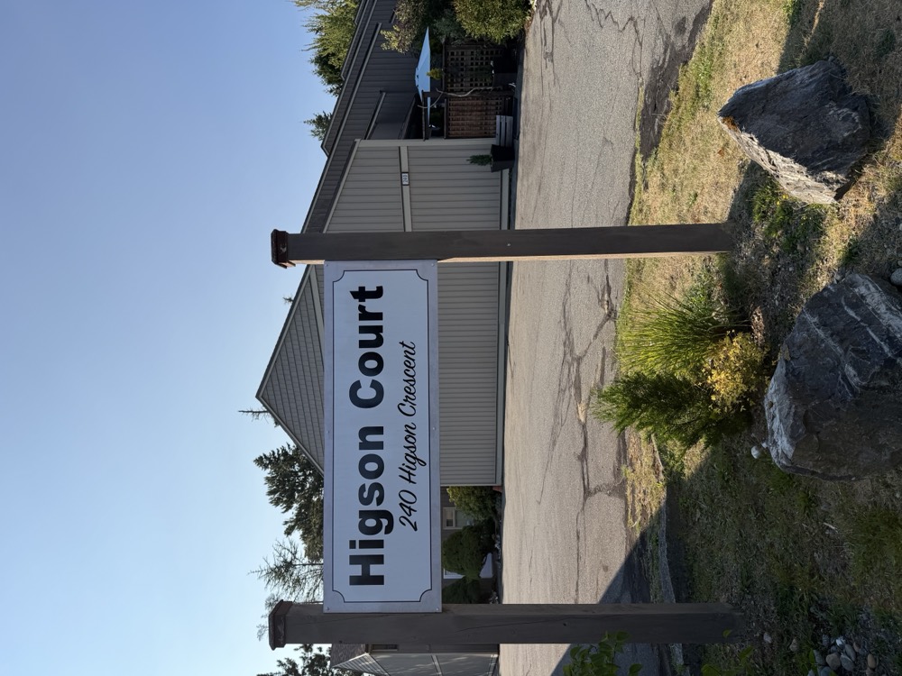 The Higson Court entrance sign standing at the edge of the parking area, with the townhouses behind it.