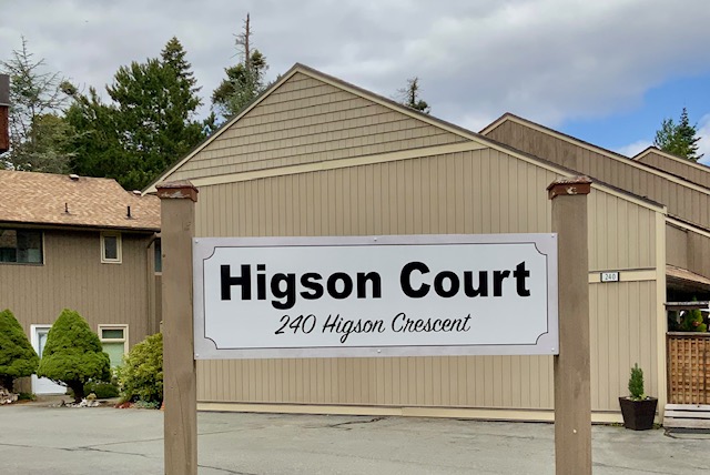 The Higson Court sign, reading 240 Higson Crescent, mounted on posts in front of a cedar-sided building.